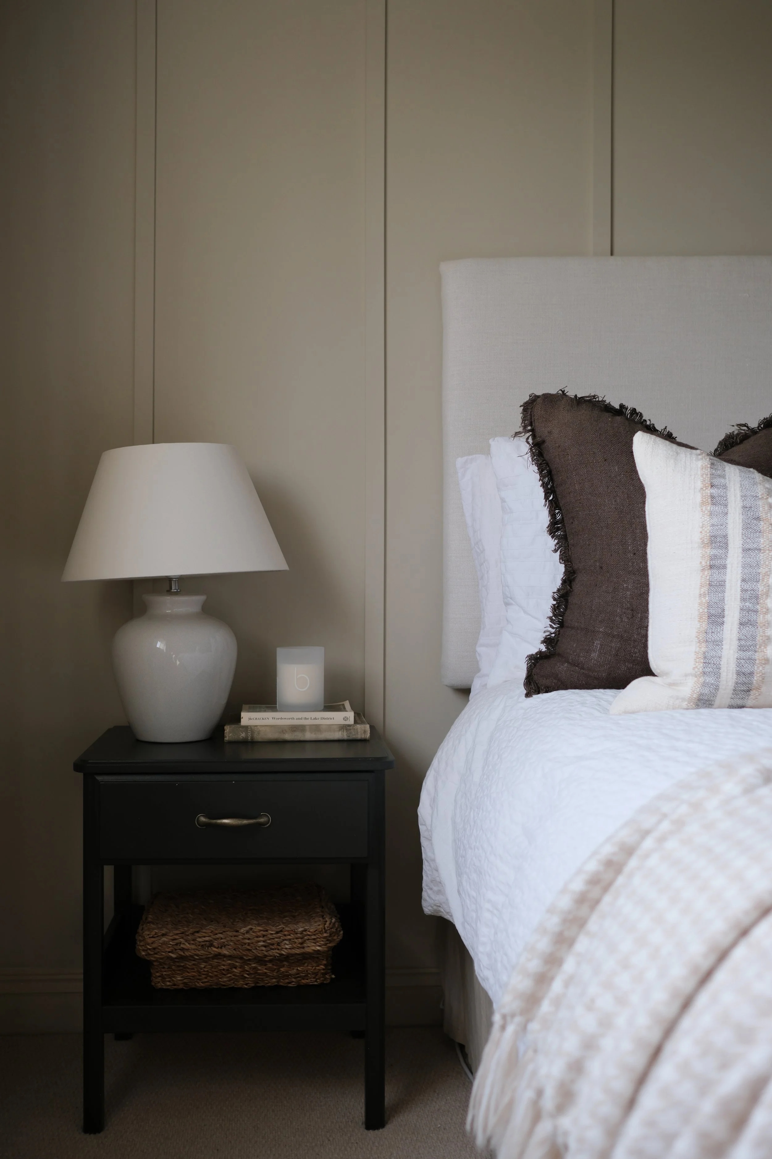 A serene bedroom with a layered bed and soft lighting, showcasing modern country interiors by a high-end interior designer in Gloucestershire, South West.