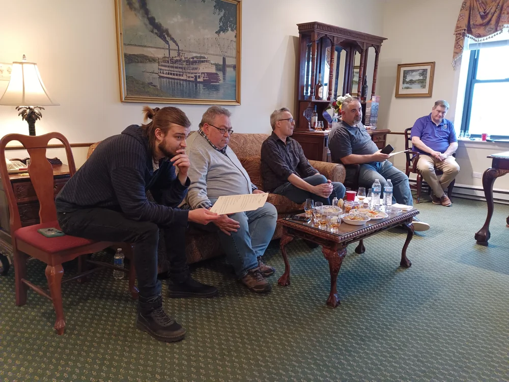 Various Delt Alumni sit and listen to a guest speaker while sipping drinks.