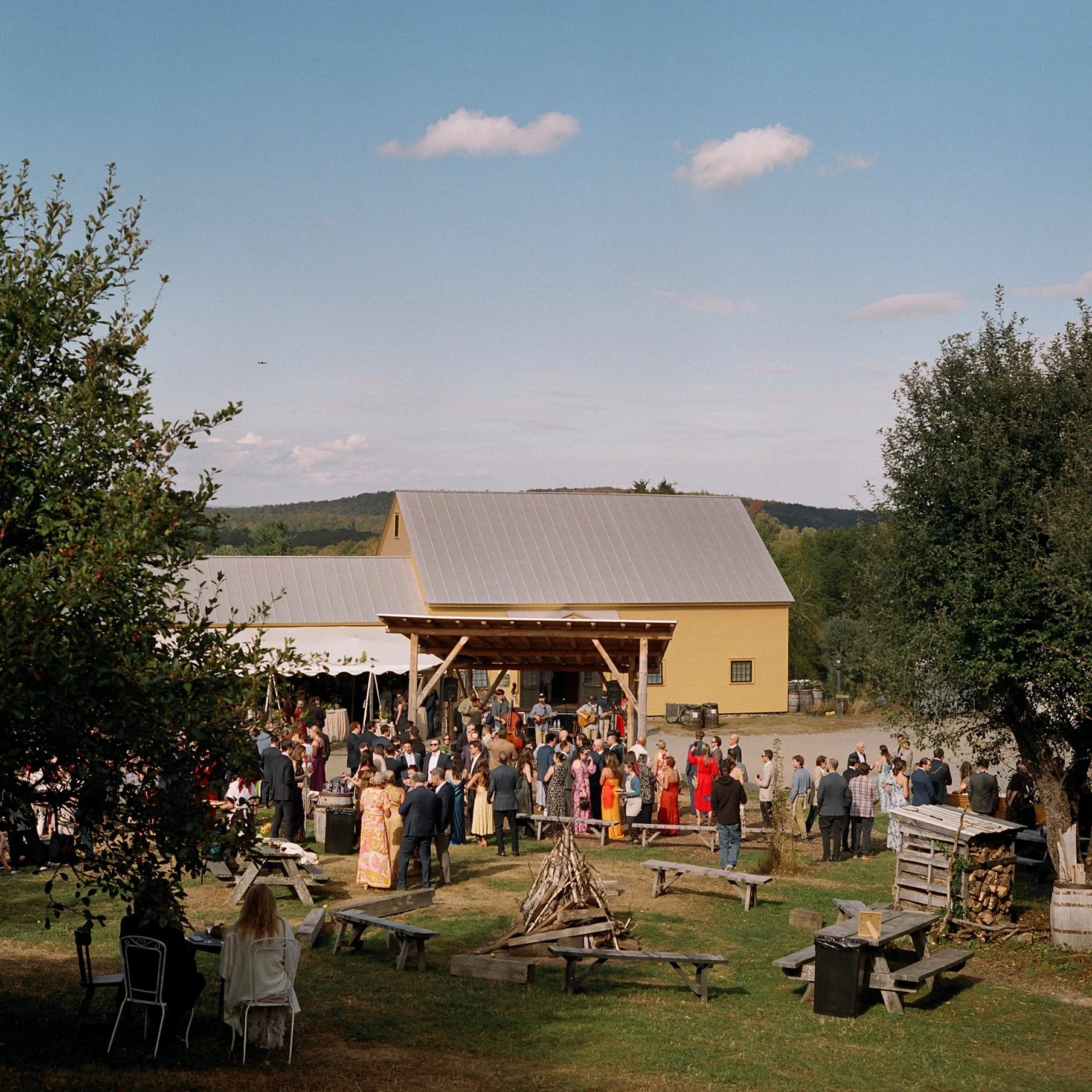 film photo of guests gathering near fire pit before it is lit