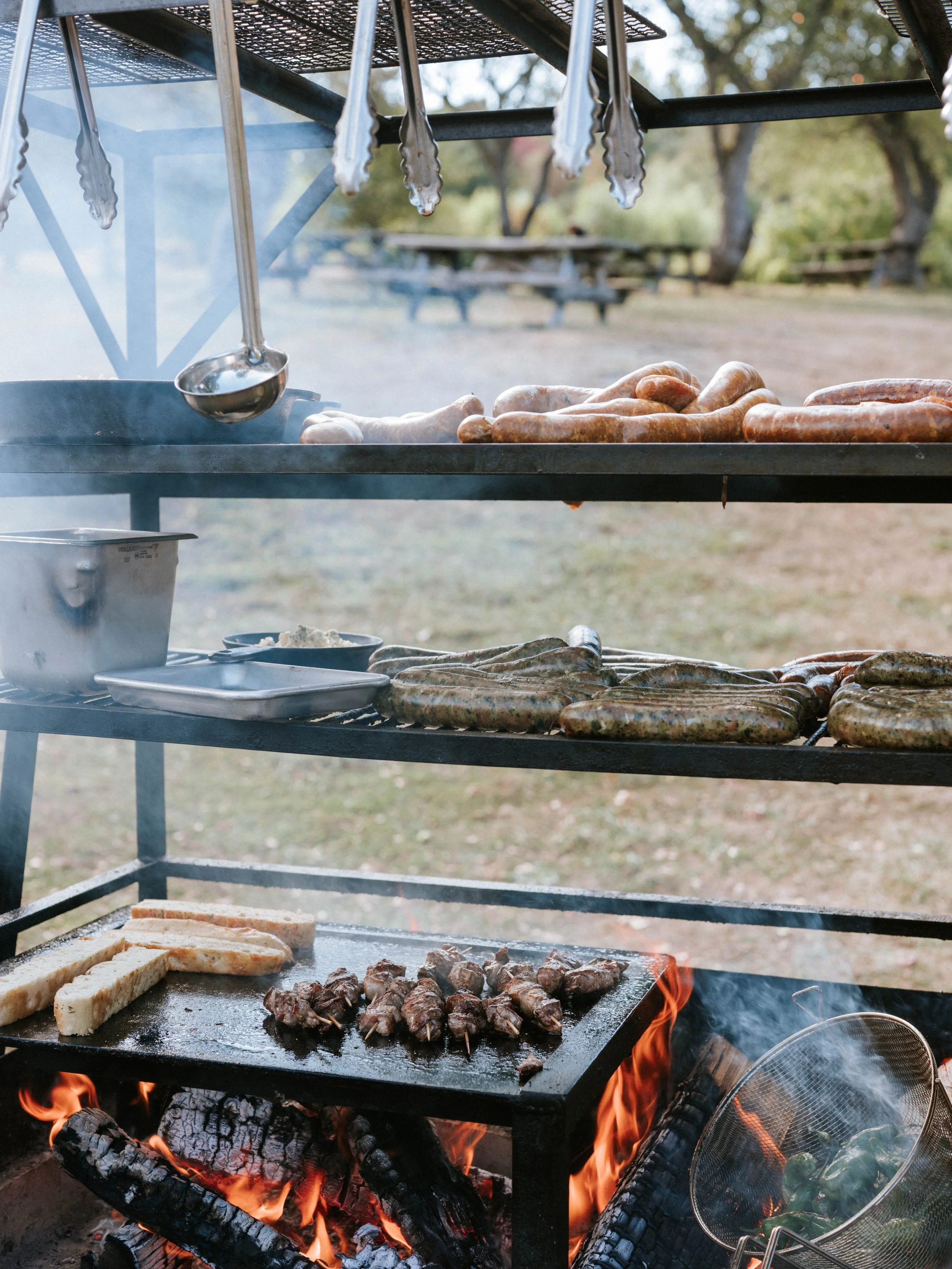 farm to table cooking in the orchard with sausages and chicken over a fire