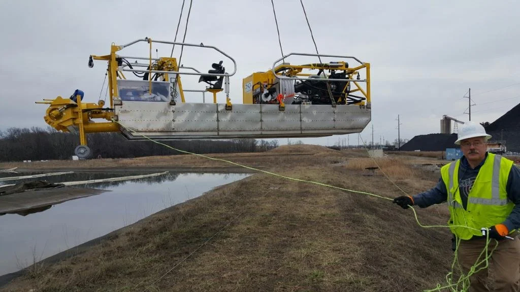 Construction worker holding a rope near a suspended large drilling or excavation machine at a construction site on overcast day.