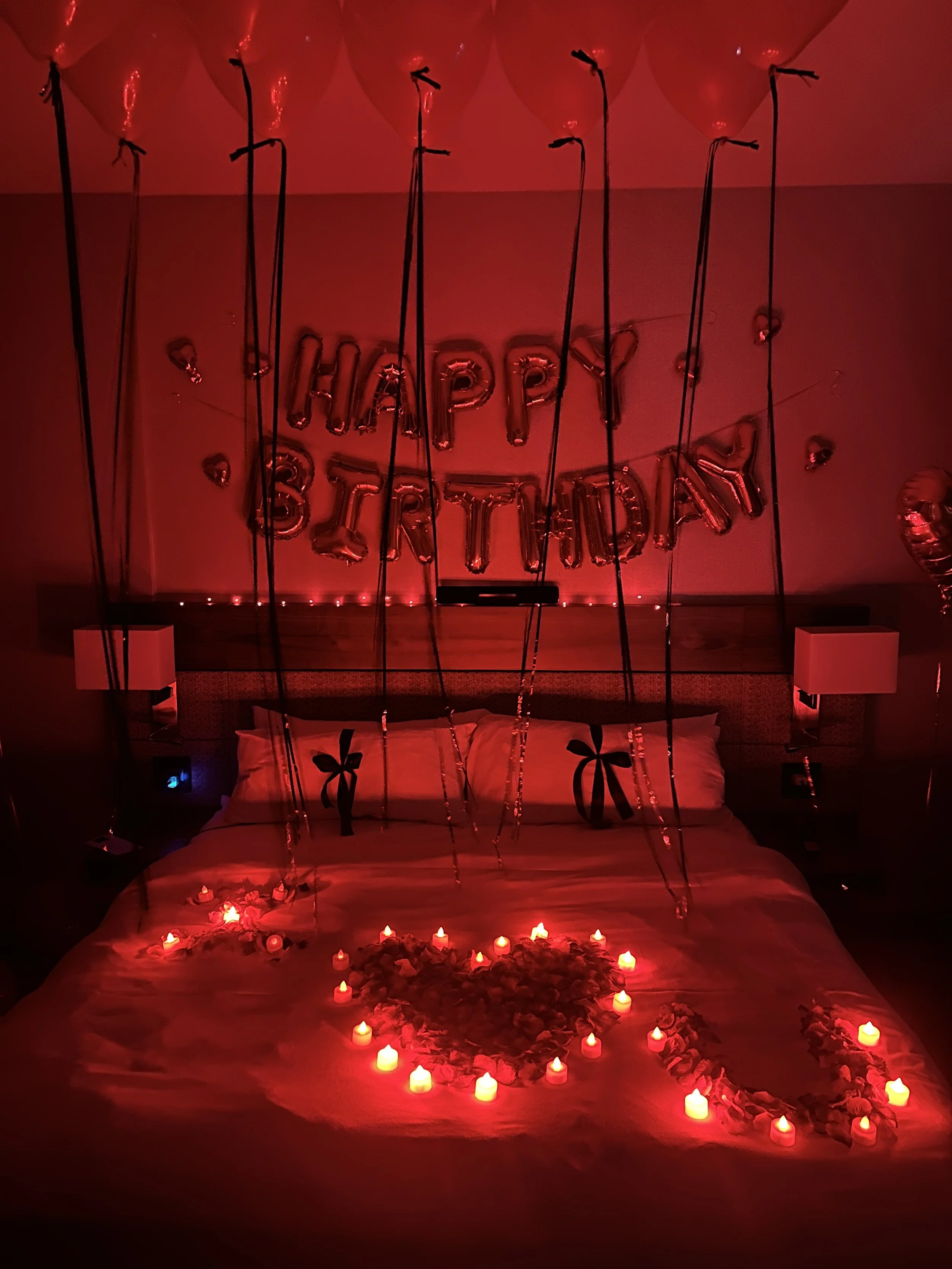Celebratory bedroom decorated for a 35th birthday with blue and silver balloons, large number balloons '3' and '5', a bouquet of red roses, and a 'Happy Birthday' banner in the background at an Airbnb in Denver, co