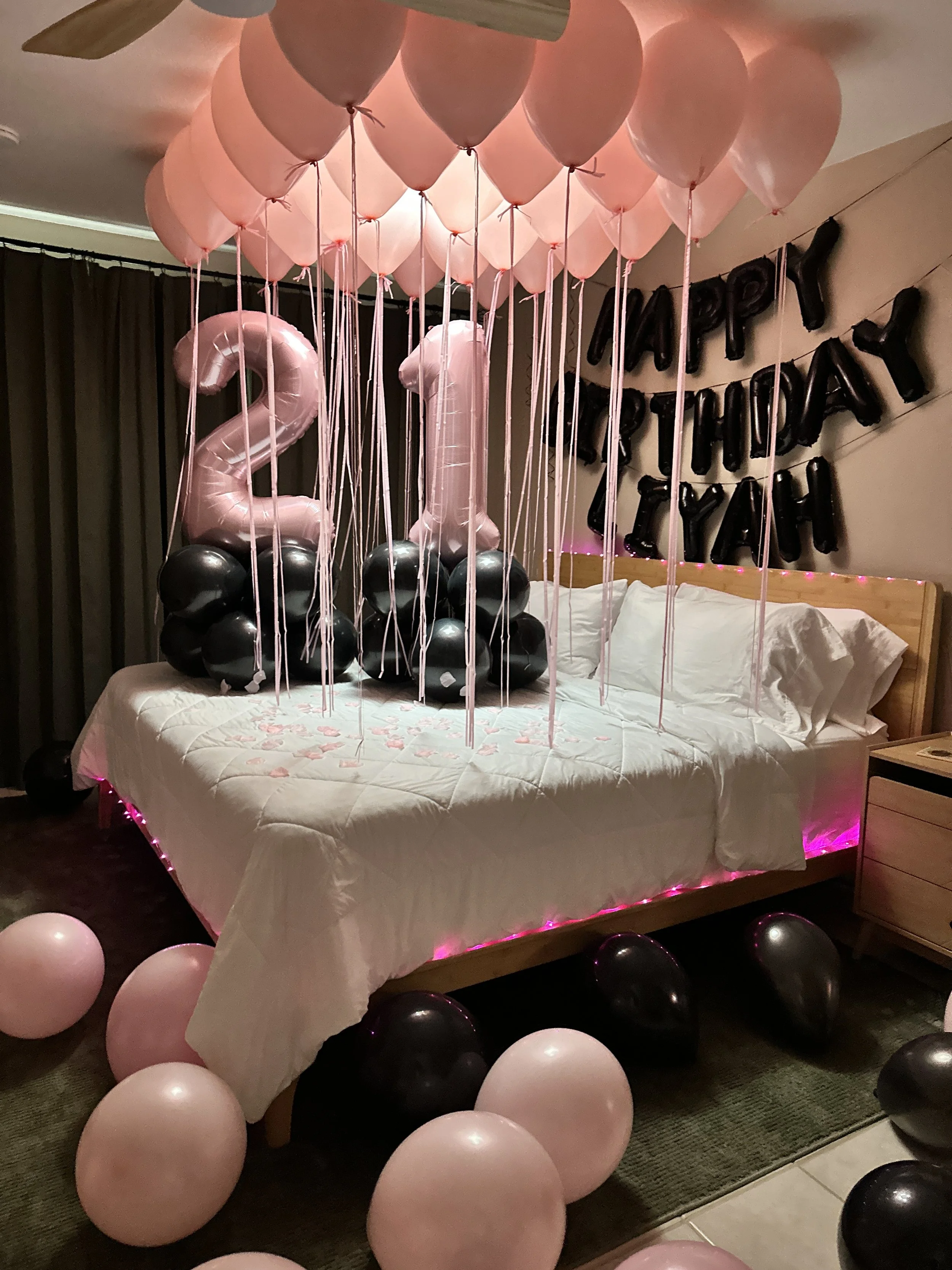 Decorated hotel room with pink and white balloons, silver '26' balloon, 'Happy Birthday Mamas' balloons, pink bouquet, and balloons on bed for a birthday celebration in Denver, Co.