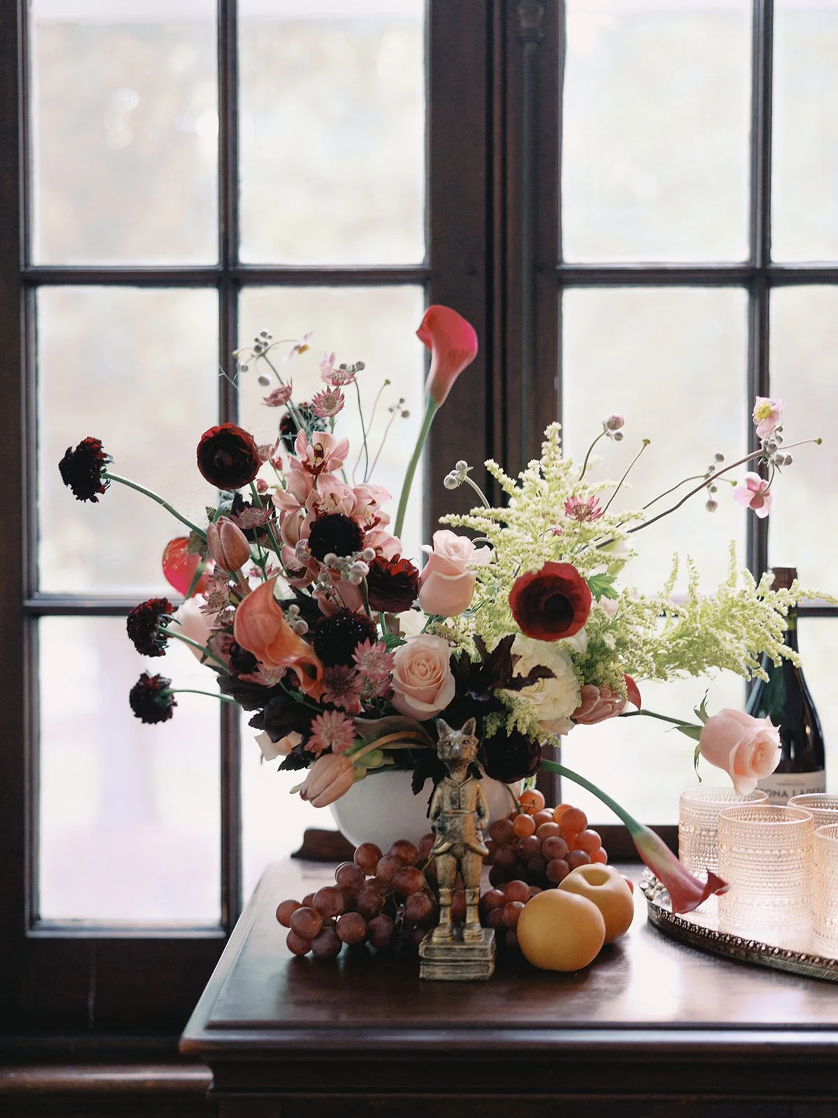 Sculptural wedding bar arrangement with cascading blooms and seasonal flowers beside the cocktail area at Hill House in Durham, NC.