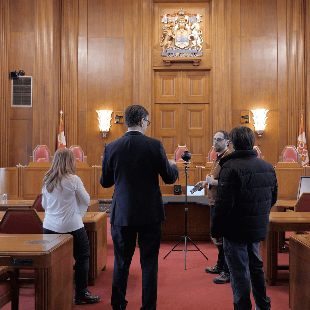 Four people talk around a 360 camera in the Supreme Court of Canada