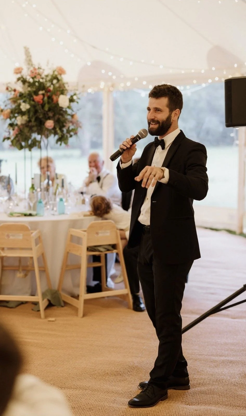 Wedding celebrant speaking at Chloe and Danny’s elegant reception under a marquee with fairy lights and floral centrepieces