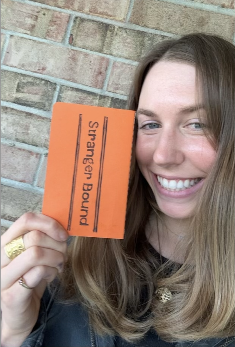 Person holding an orange stranger bound journal.