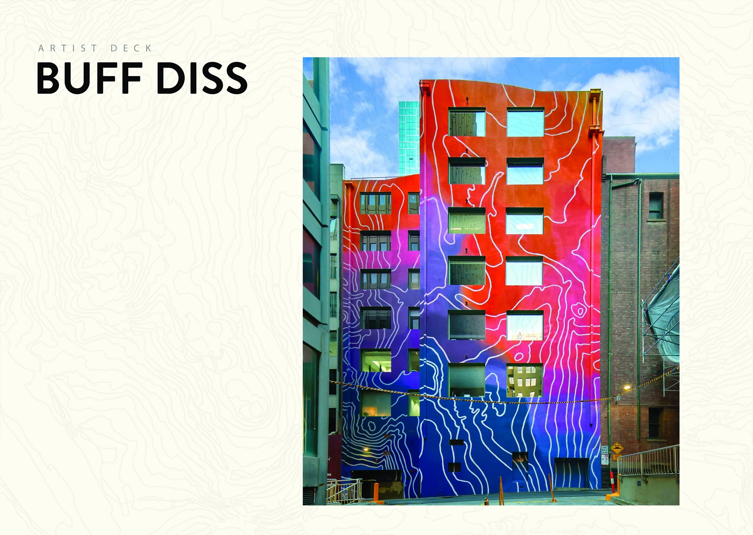 Colorful building with abstract mountain topographic pattern painted on its red and purple facade, set against a blue sky with clouds.