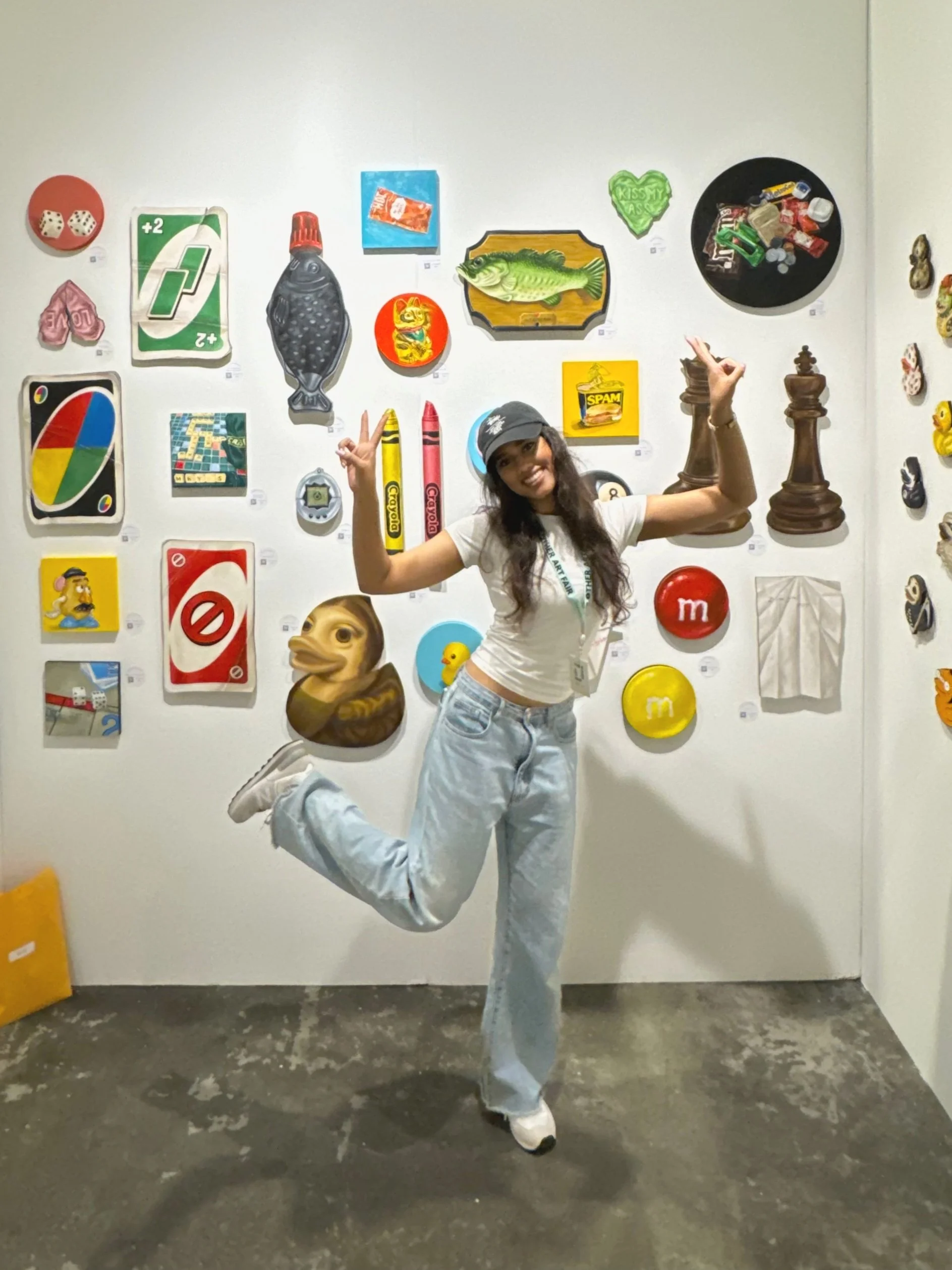 Dilara posing in front of a wall with colorful pop art icons and objects.