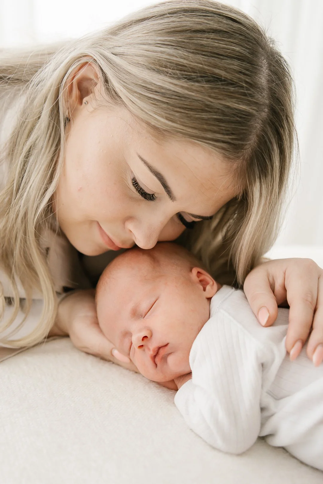 Nuori nainen halaa ja hyväilee nukkuvaa vauvaa, pitelee häntä kädessään