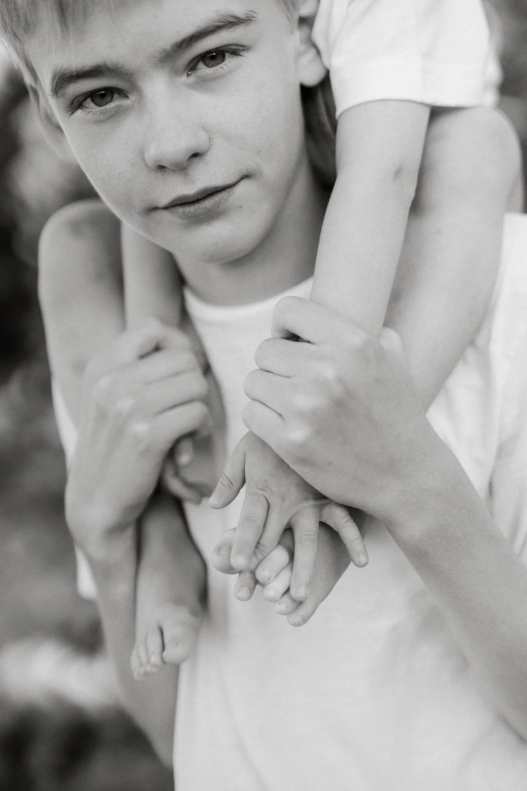 Mustavalkoinen valokuva nuoresta miehestä, joka pitää lapsen käsistä kiinni.