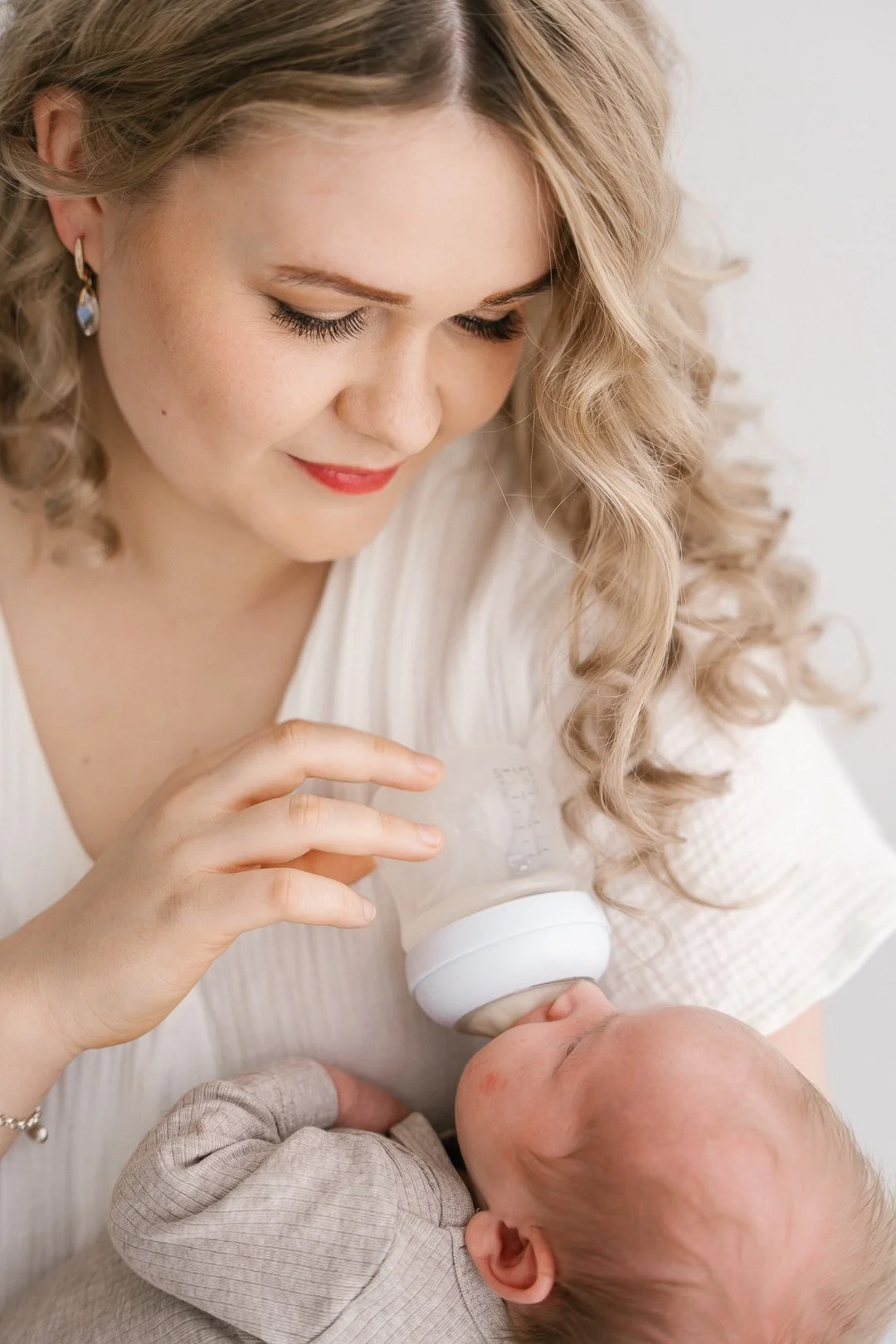 Naisellinen nainen ruokkii vastasyntynyttä lasta pullolla.