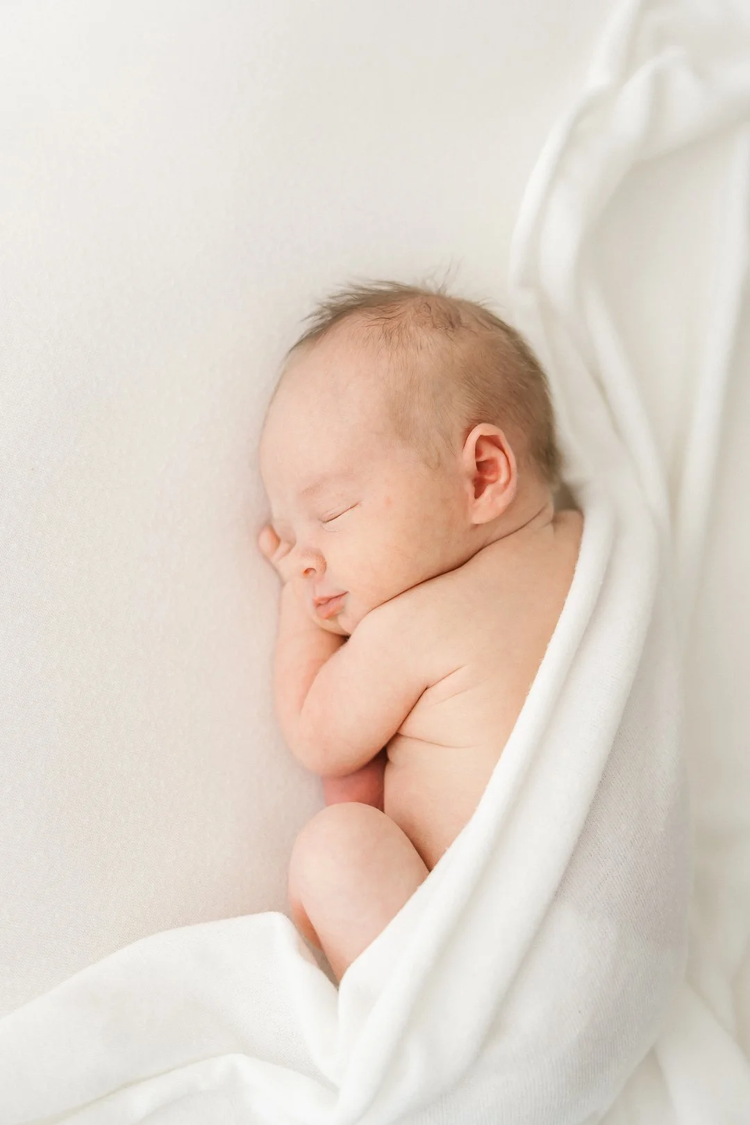 Uuta vauvaa nukkuvana vaalean taustan vieressä.