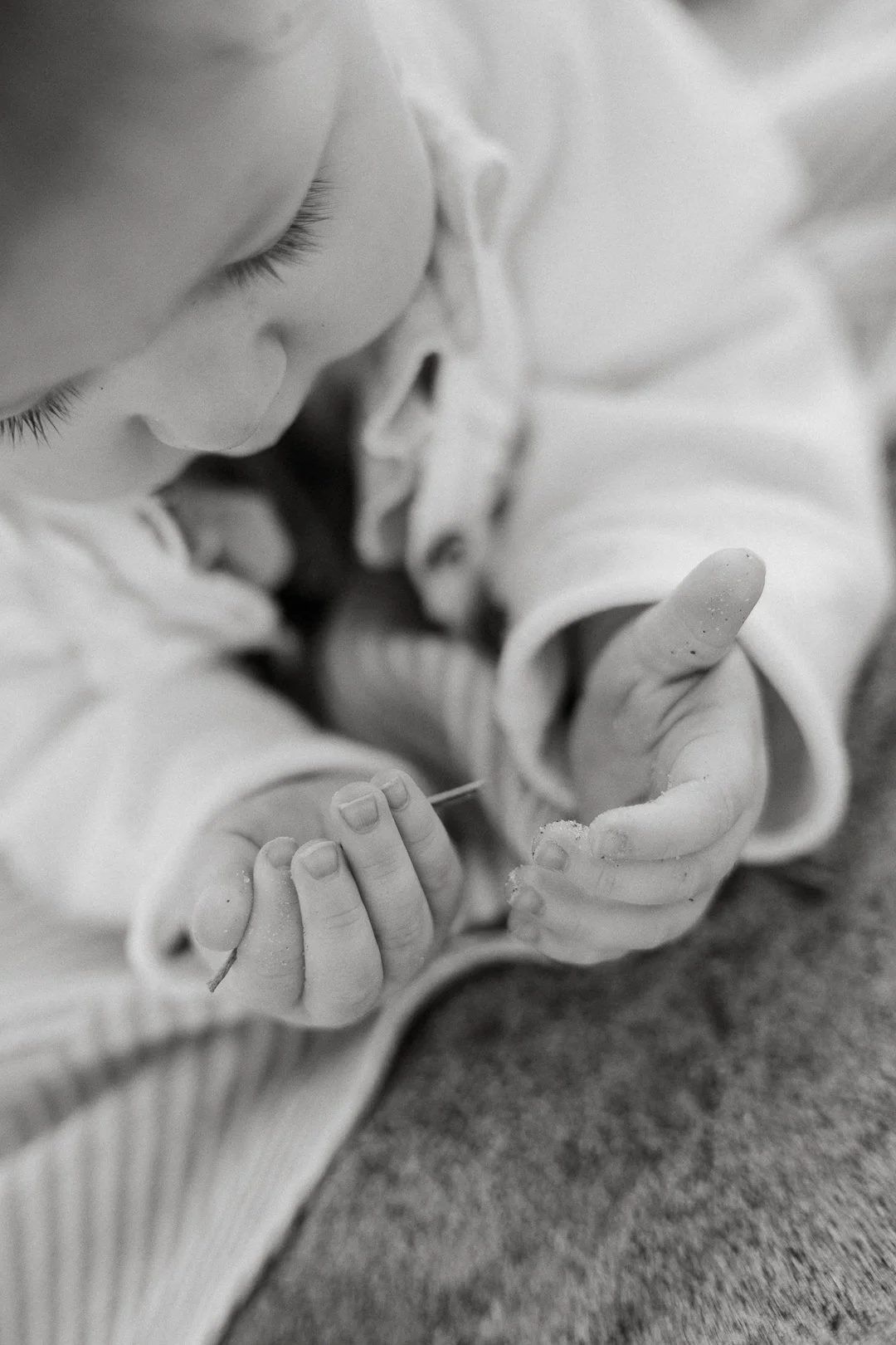 Mustavalkoinen kuva lapsesta, joka leikkii ja tutkii maata pihalla.