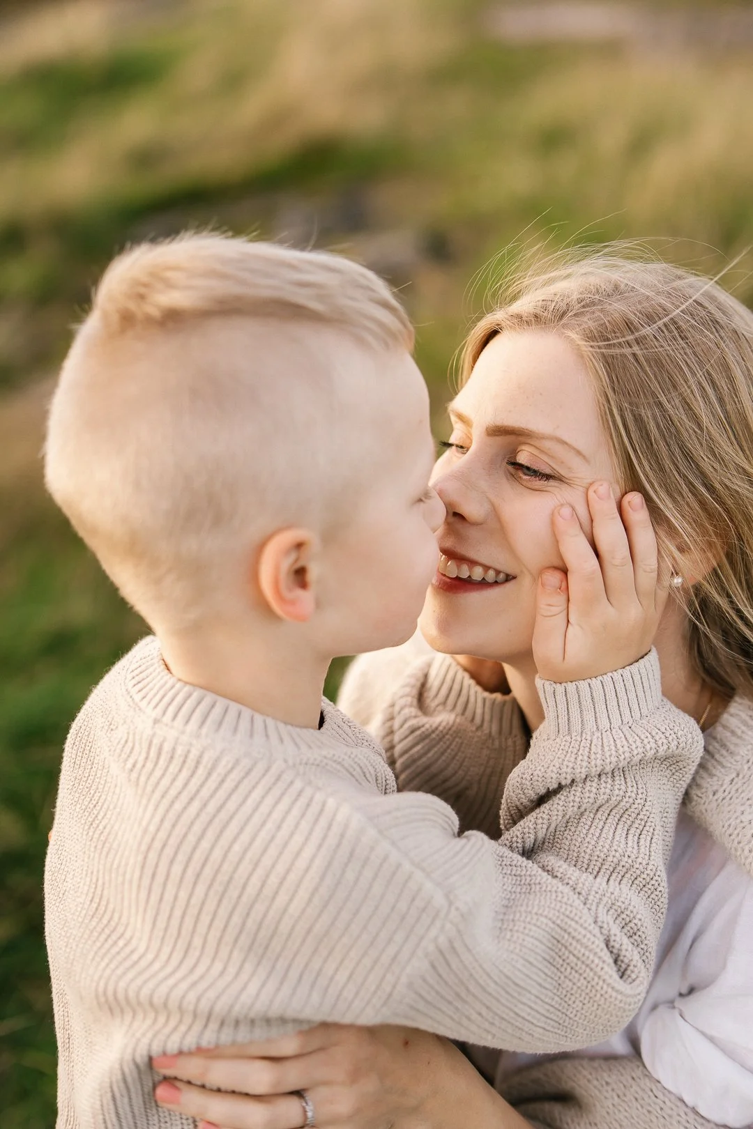 Nuori poika ja nainen lähekkäin, halaavat ja katsovat toisiinsa rakastavasti ulkona ilta-auringossa.