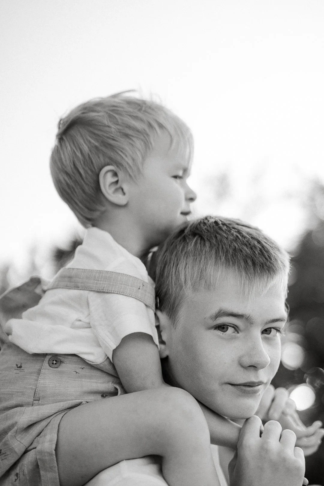 Mustavalkoinen valokuva kahdesta pojasta, joista vanhempi kantaa nuorempaa selässään.