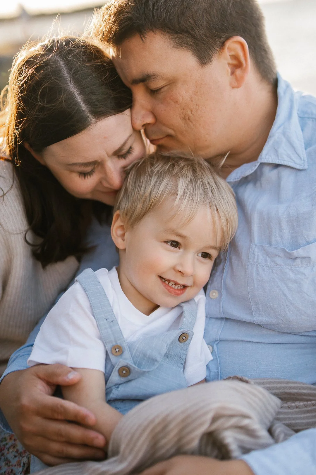 Perhe halailee ja hymyilee yhdessä ulkona auringonlaskun aikaan.