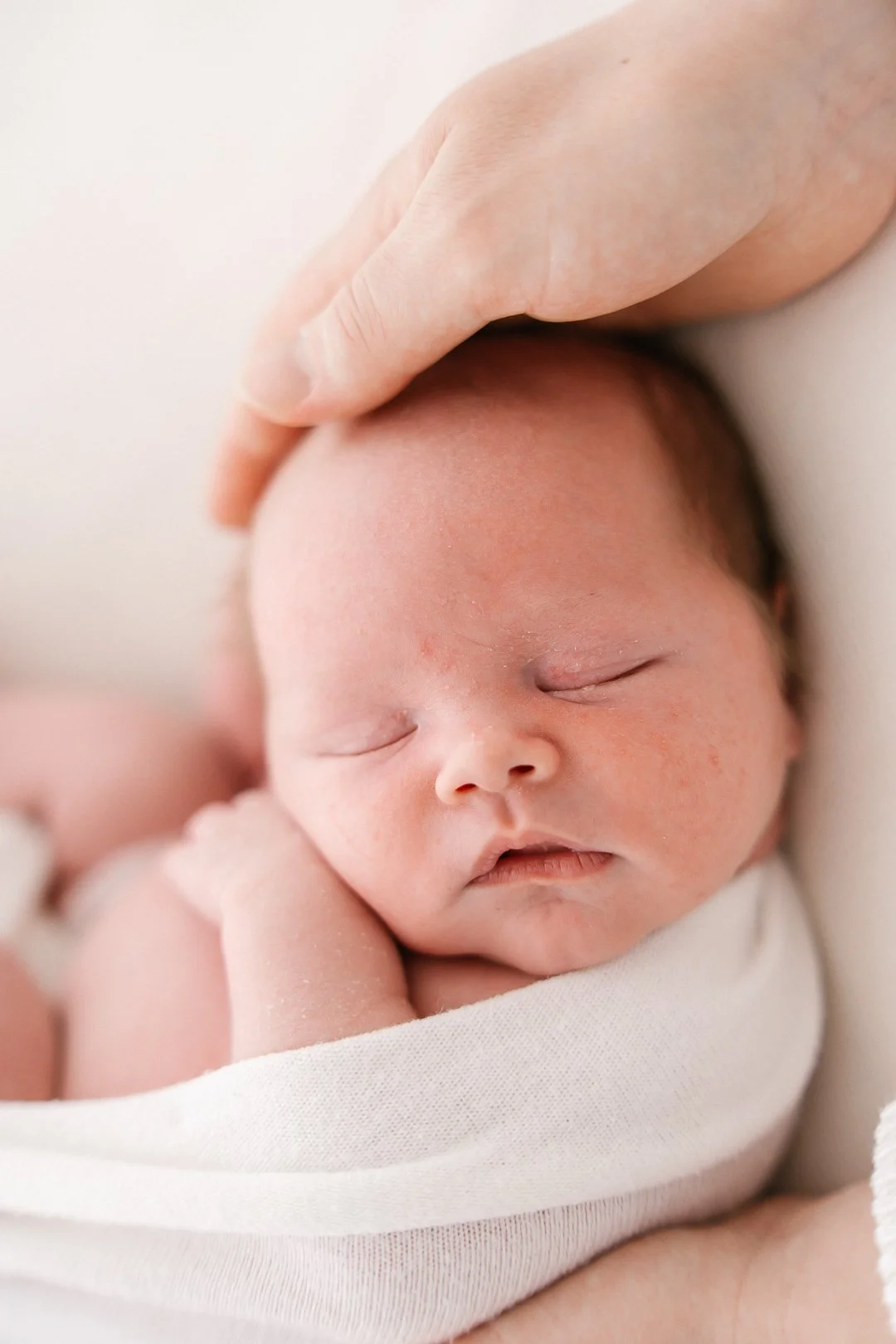 Uinuva vauva, kiedessä äidin tai hoitajan käden päälle.