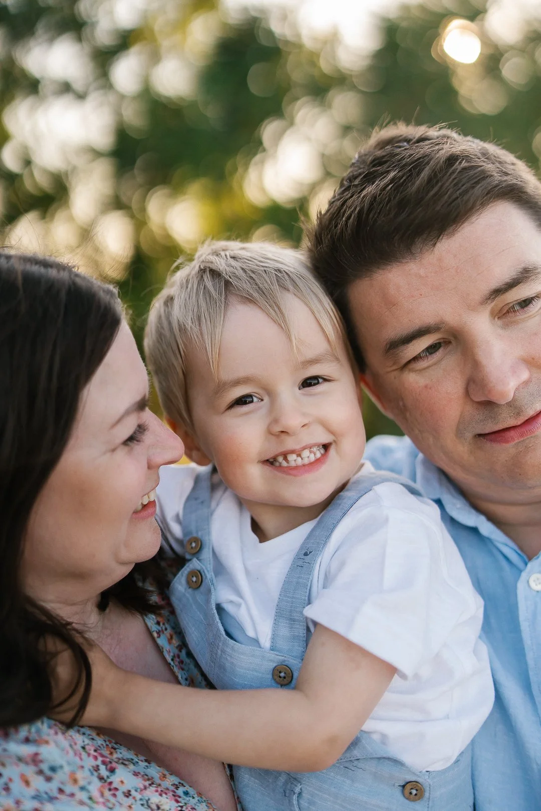 Perhe hymyilemässä ulkona luonnossa.