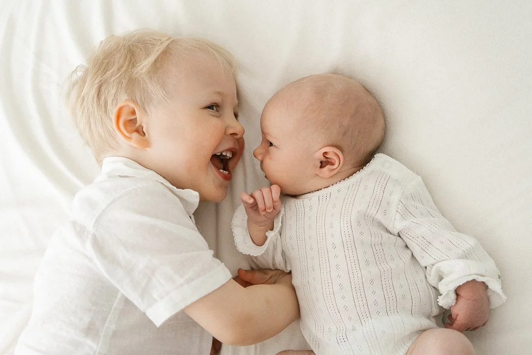 Kaksi pientä lasta leikkii yhdessä makuuhuoneessa.