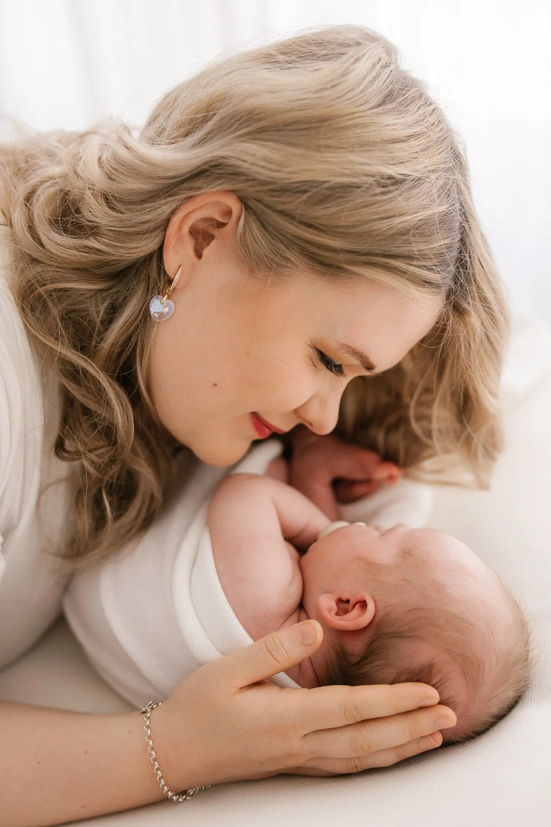 Nuori nainen hellästi katsomassa vastasyntynyttä vauvaa, jonka hän pitää käsissään yhteisellä juoksussa.