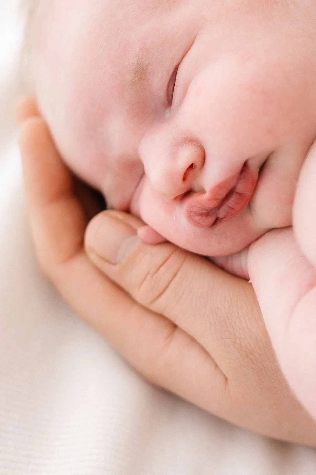 Lapsi nukkuu, huolehtivainen käsi tukee hänen päätään.