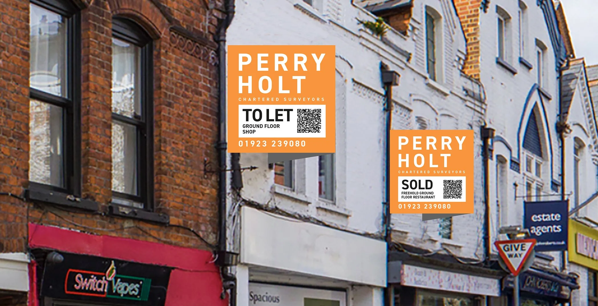 Street view with brick and white buildings, featuring signs from Perry Holt Chartered Surveyors, including 'To Let' and 'Sold' notices, and a shop sign for 'Switch Vapes.'