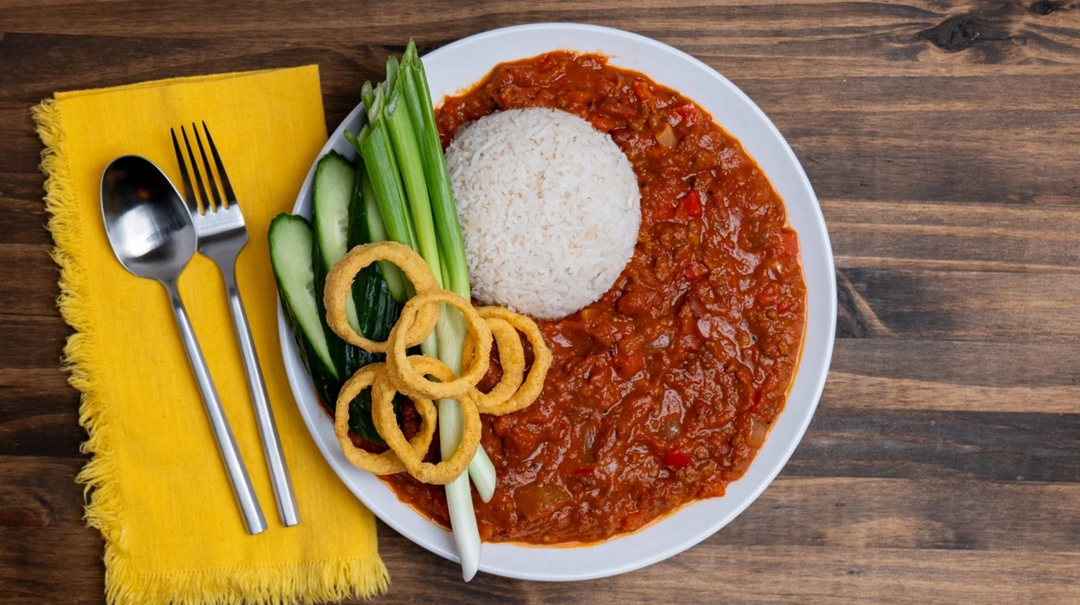 Chili plated with rice, cucumber, green onion and Funyuns.