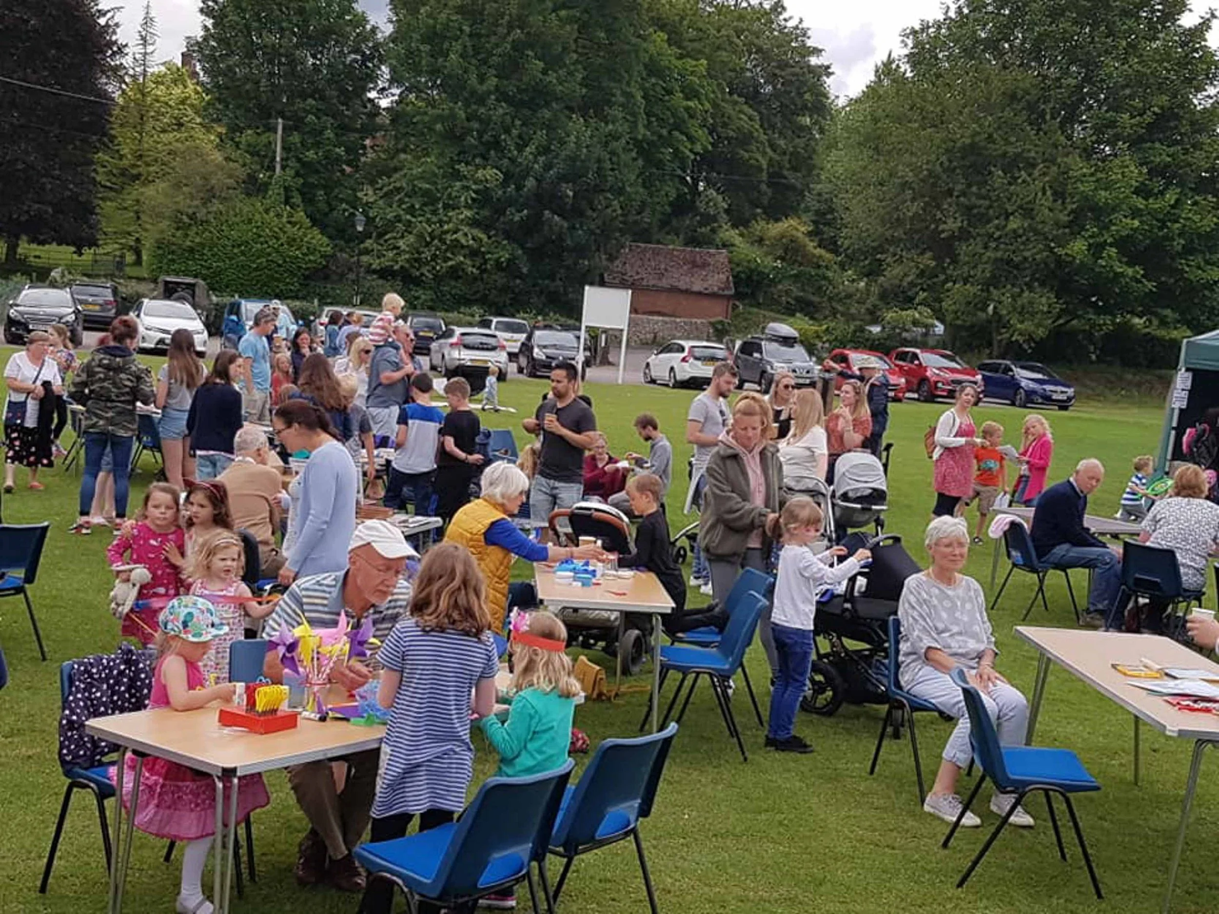 Field with tables and chairs set up as stalls and people visiting the stalls