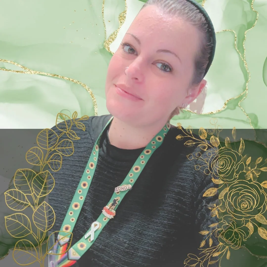 A woman with fair skin and dark hair tied back, smiling at the camera, wearing a black shirt and a colorful lanyard with pins, against a background with decorated green and gold elements.