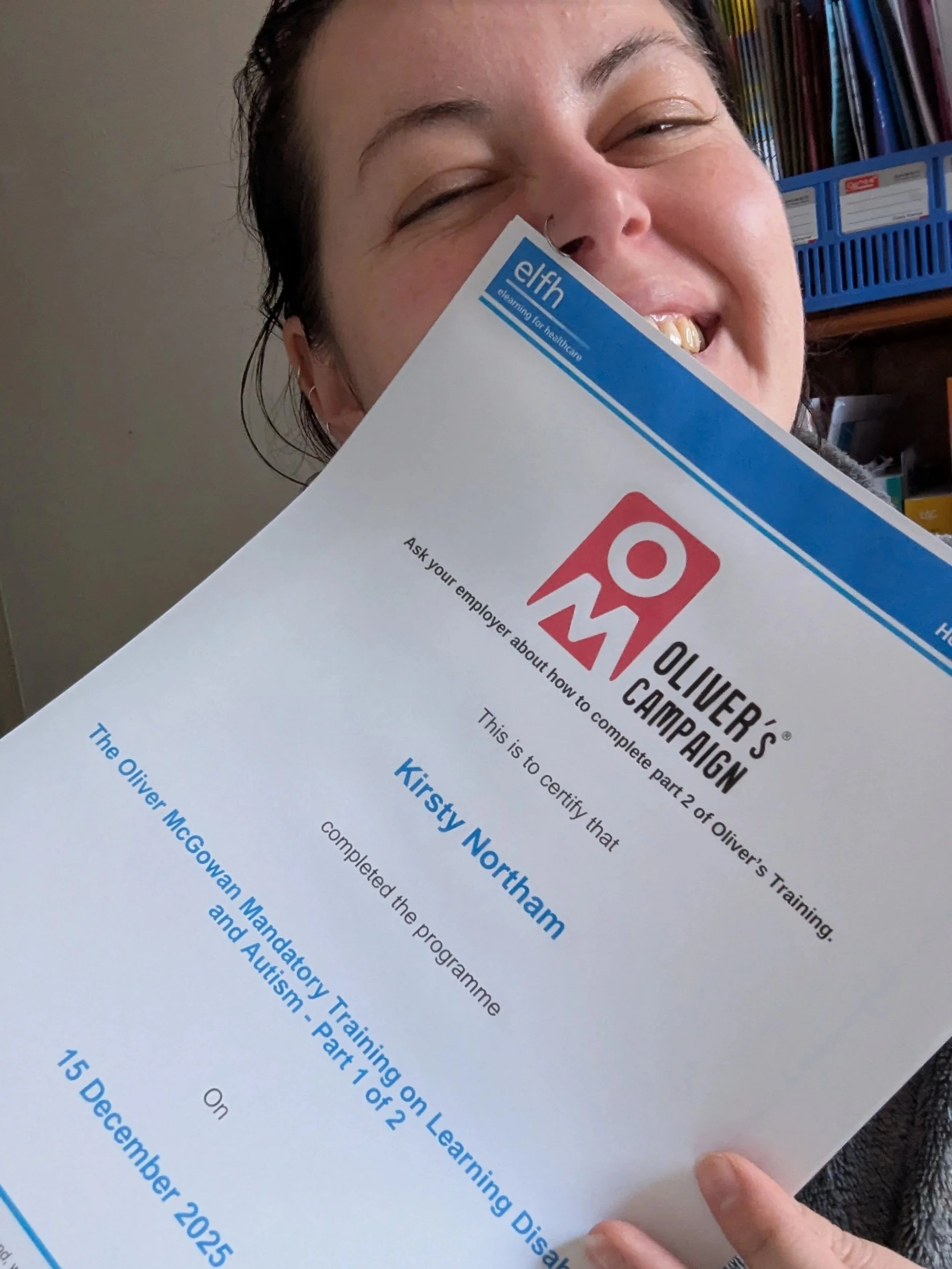 Woman smiling and holding a certificate from Oliver's Campaign for completing training on Learning Disabilities and Autism, part 2, dated December 15, 2025.