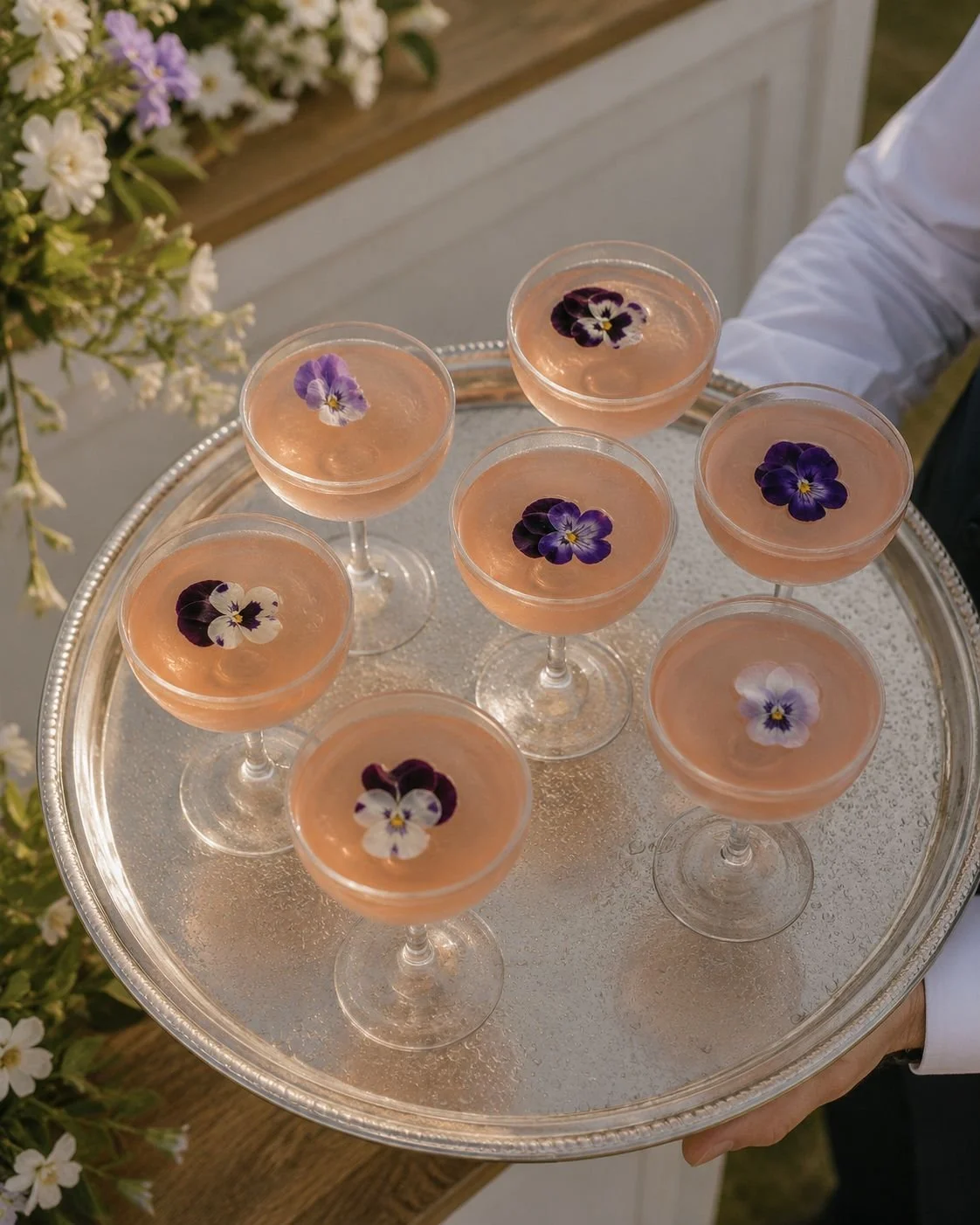 Elegant rose gin cocktails presented on a silver tray by a professional waiter, perfect for weddings and special events.