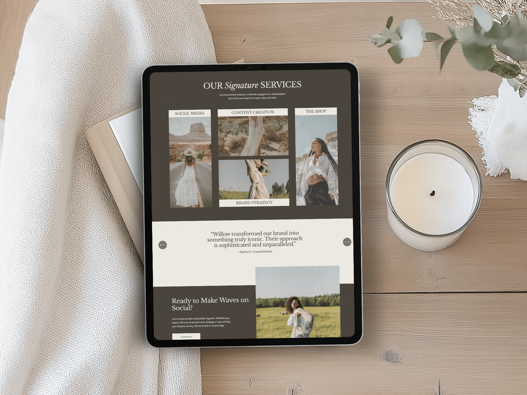 Tablet on a wooden table displaying a website with the title 'Our Signature Services' and sections about social media, content creation, and shop, with images of women in outdoor settings."