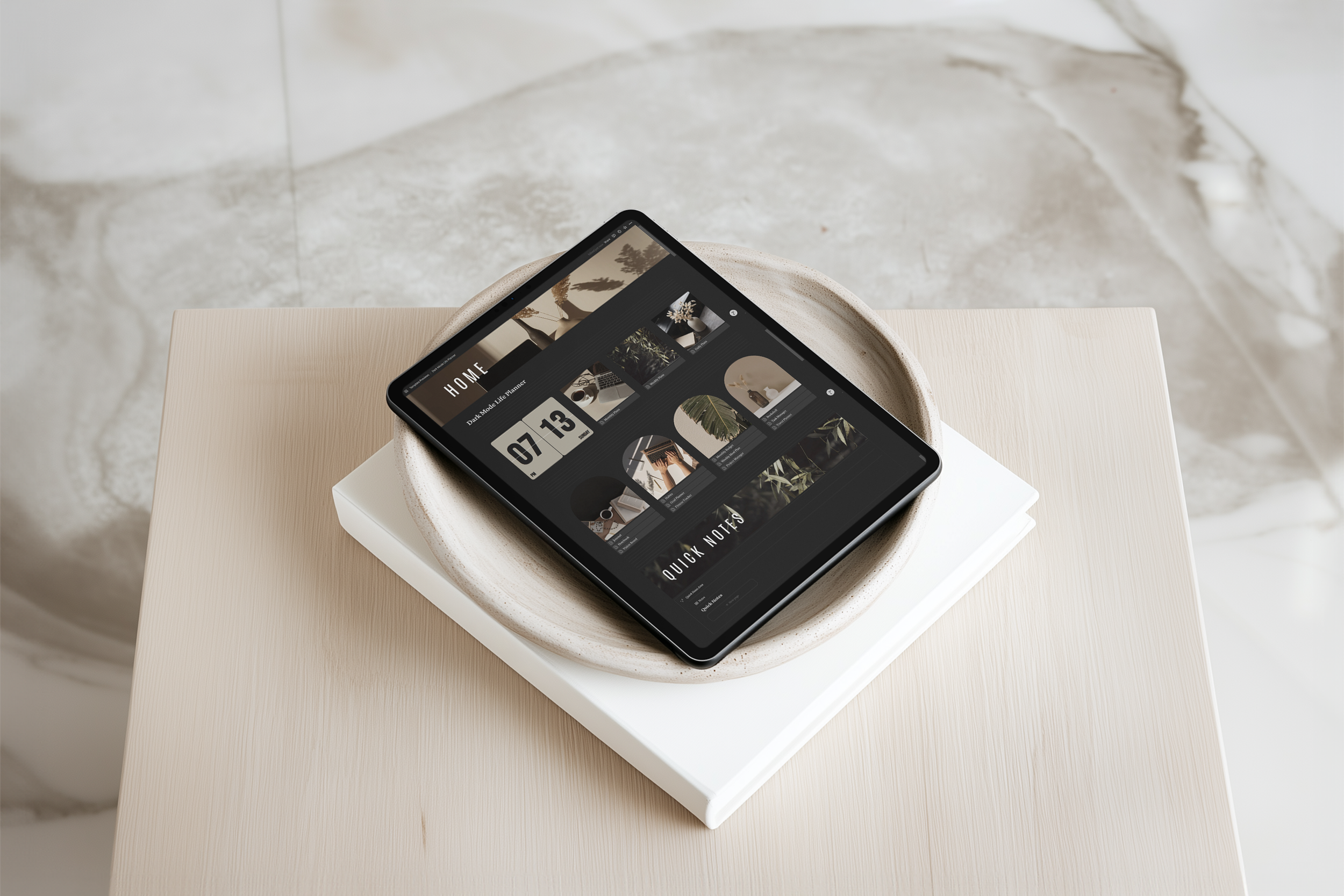 Tablet displaying a website with a dark theme, placed on a white book inside a ceramic bowl on a light-colored table.