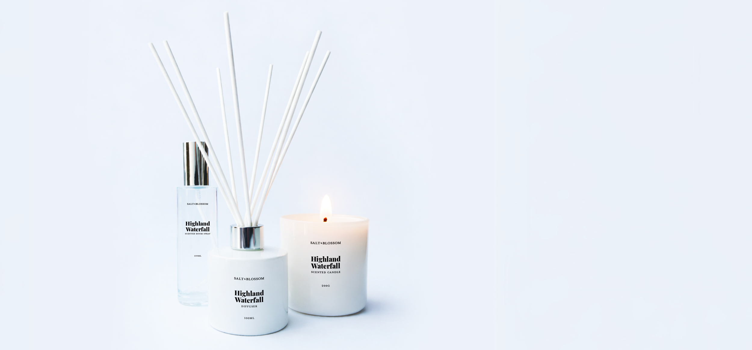 A collection of Highland Waterfall scented products, including a candle, diffuser, room spray, and reed diffuser, arranged on a white surface against a light blue background.