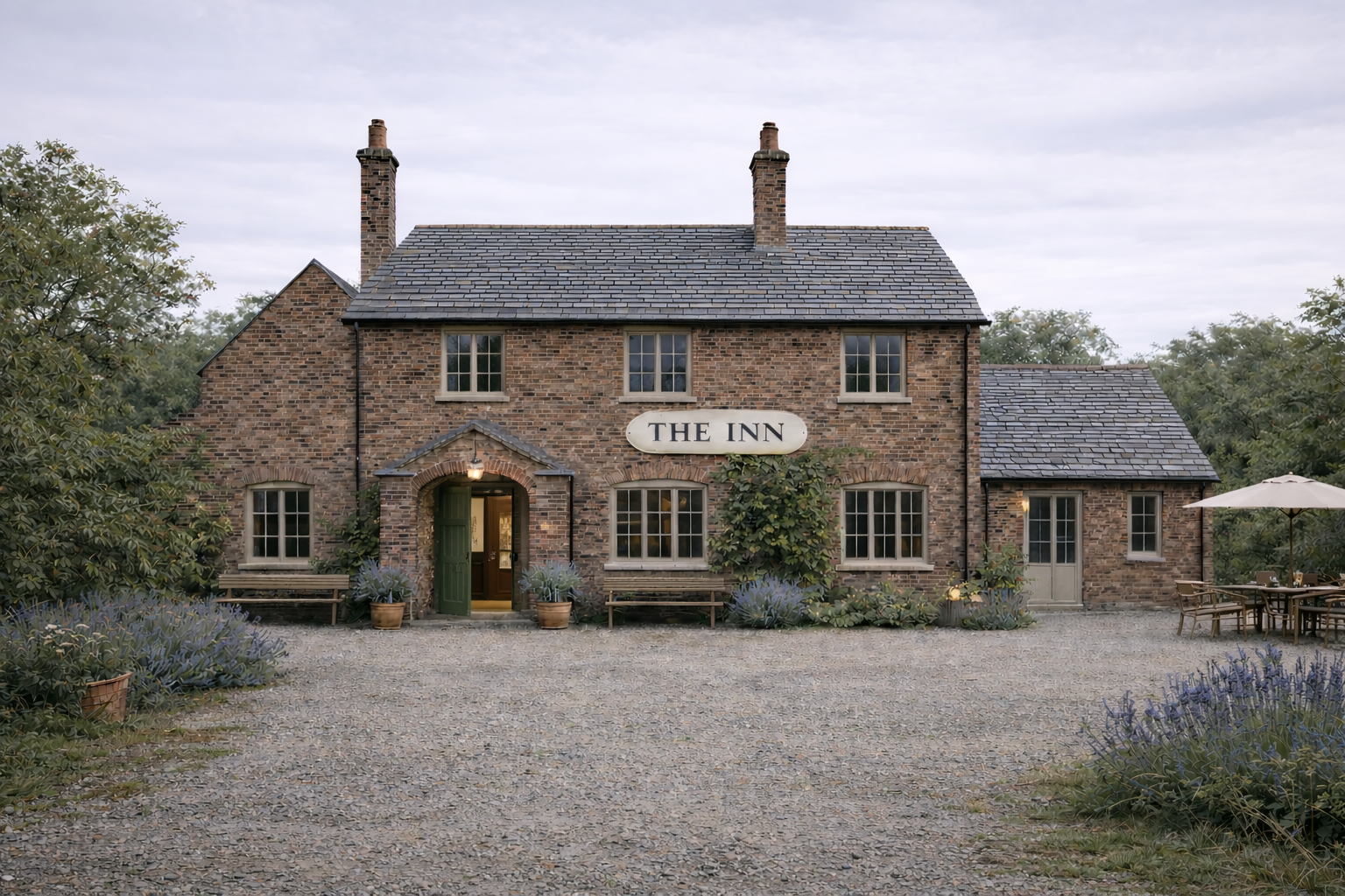 A rustic brick inn with a sign that reads 'The Inn' above the entrance, surrounded by lavender plants and outdoor seating with an umbrella, set against a cloudy sky.