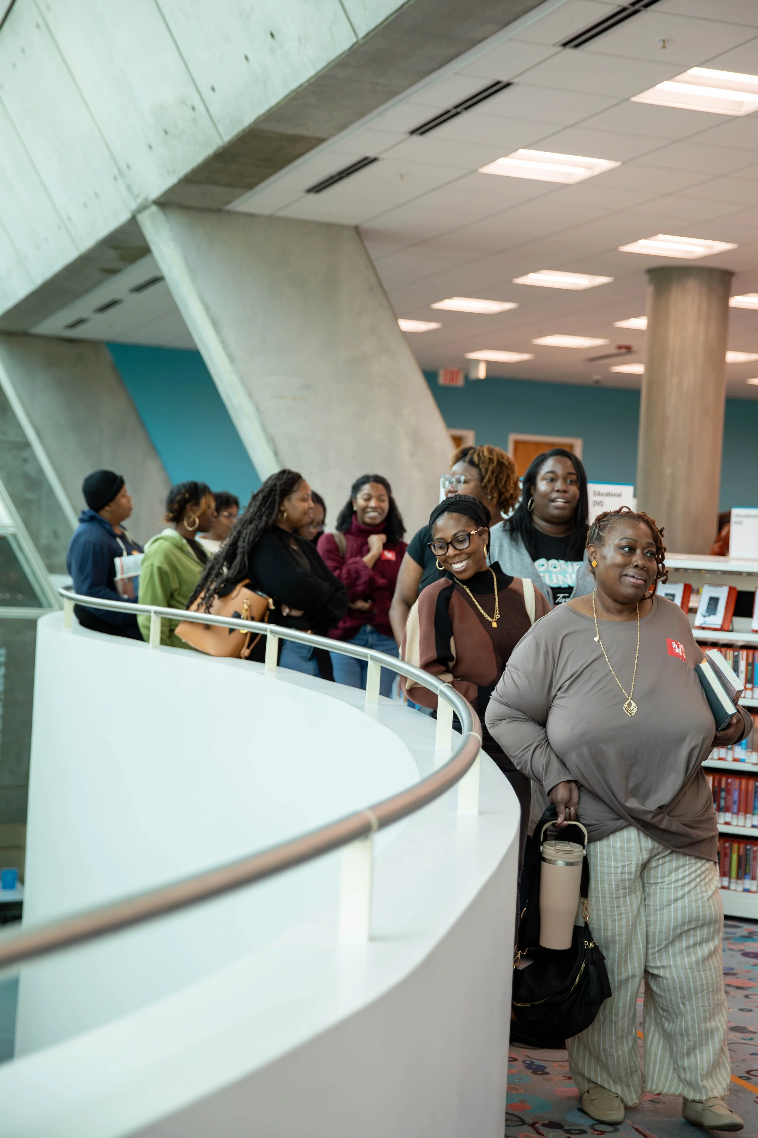 A group of diverse people standing in line inside a library.