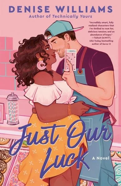 Book cover for 'Just Our Luck' by Denise Williams, featuring a Black woman with curly hair and a man with light skin and short dark hair, sharing an intimate moment in a kitchen with pink walls, a countertop, and baked goods.