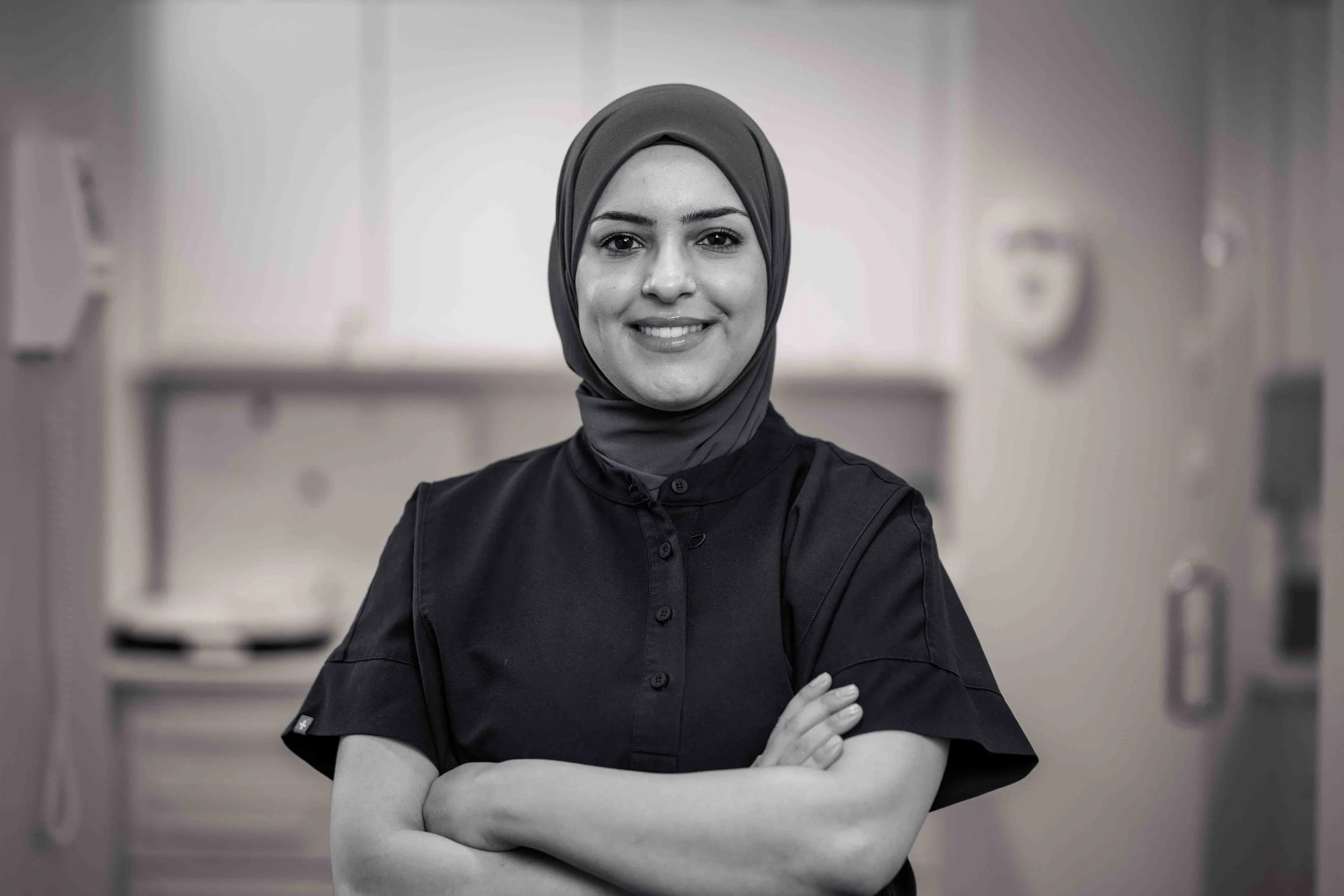 Kvinde iført sort t-shirt og beige hijab står foran en farvetegning med tekst