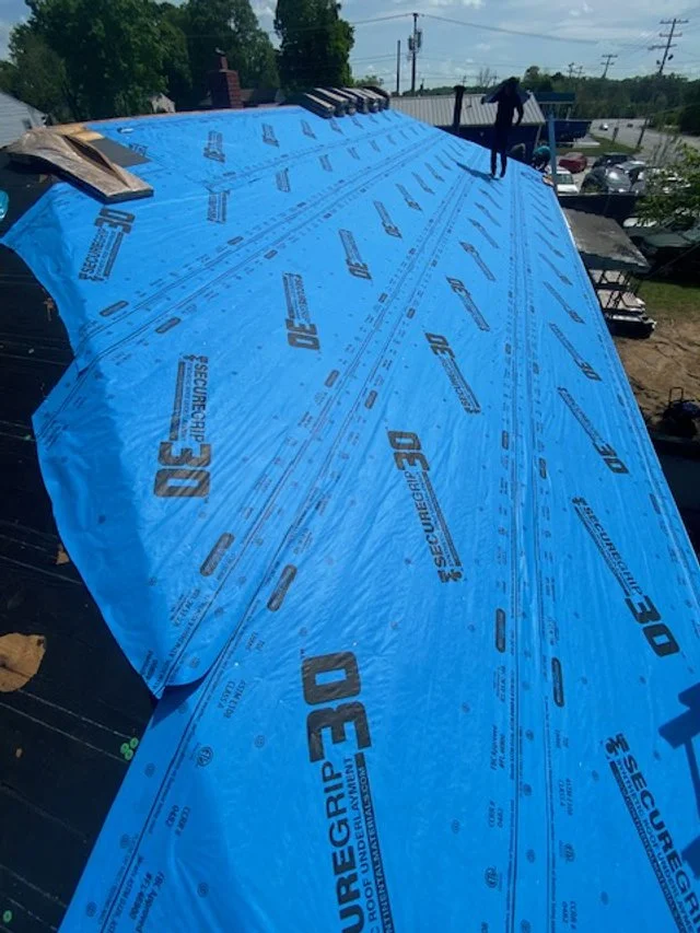 Blue roofing underlayment labeled Secure Grip 30 on a building roof during construction.