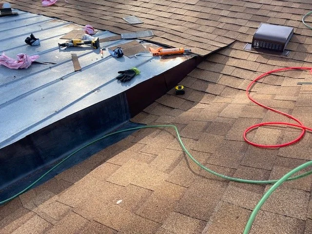 Roof shingles under repair with tools and safety gloves on the roof.