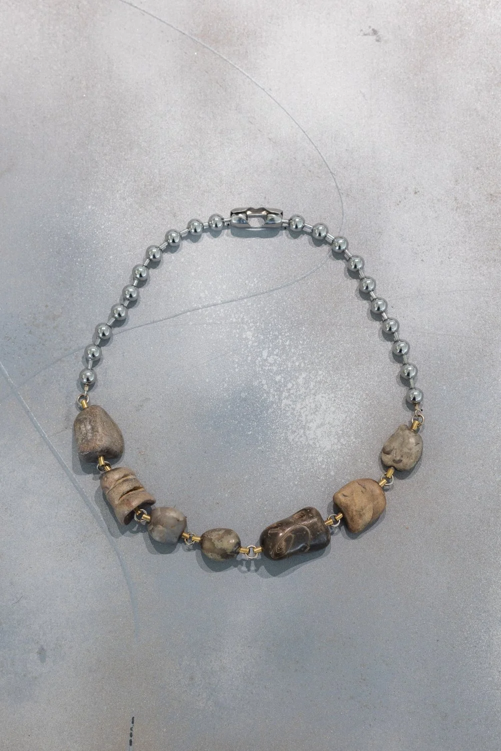 Darja Popolitova, Necklace, 2026, Baltic fossils and limestones, laser engraving, brass, steel chain, silver. Photo: Kristīne Madjare