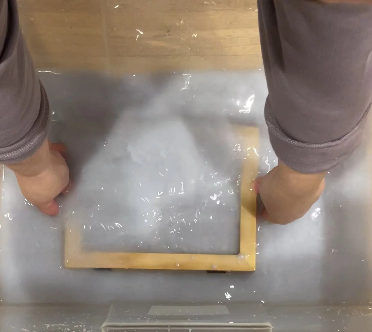 wood frame and screen submerged in paper pulp