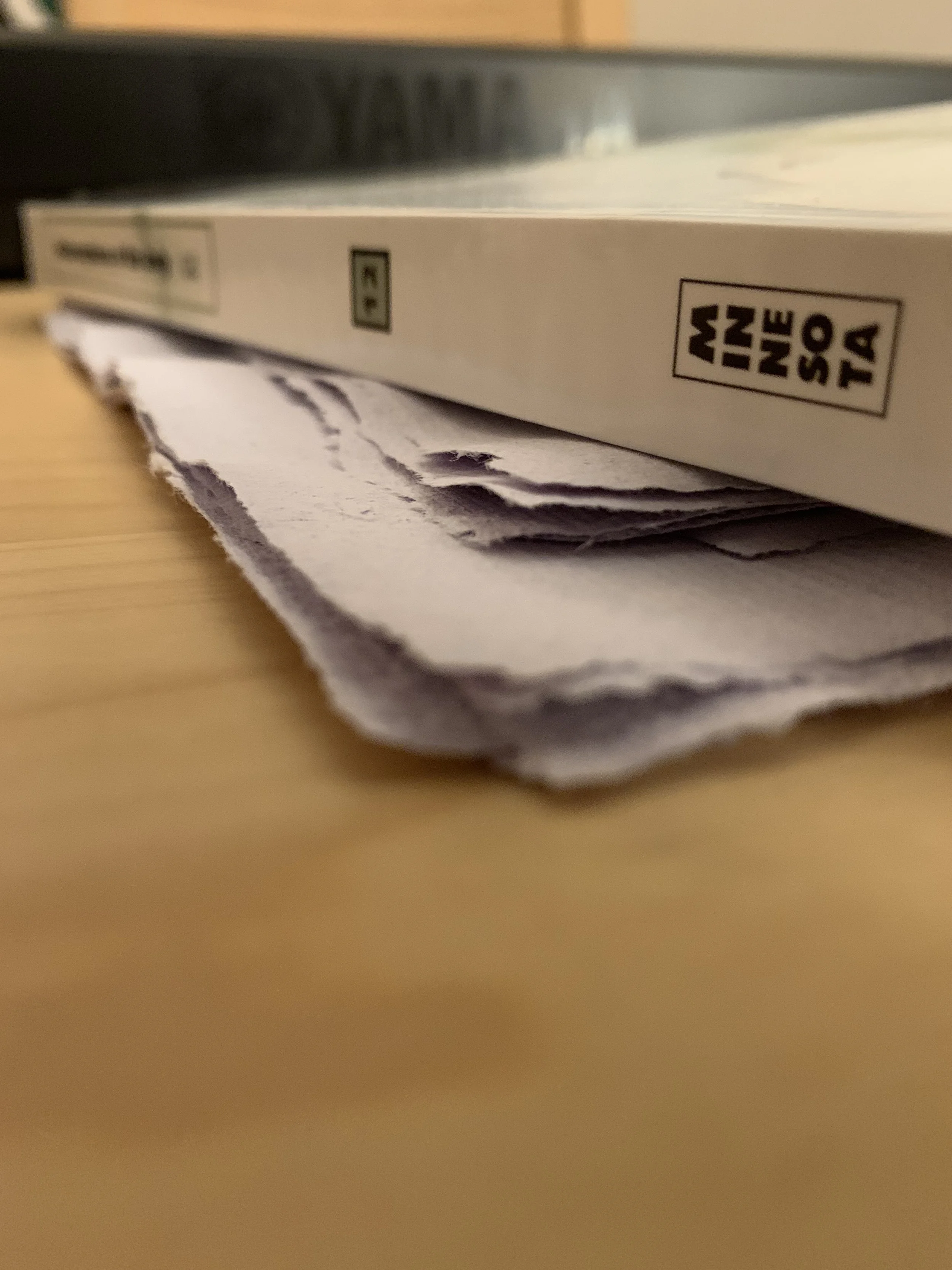 Paper being pressed under a book on a table