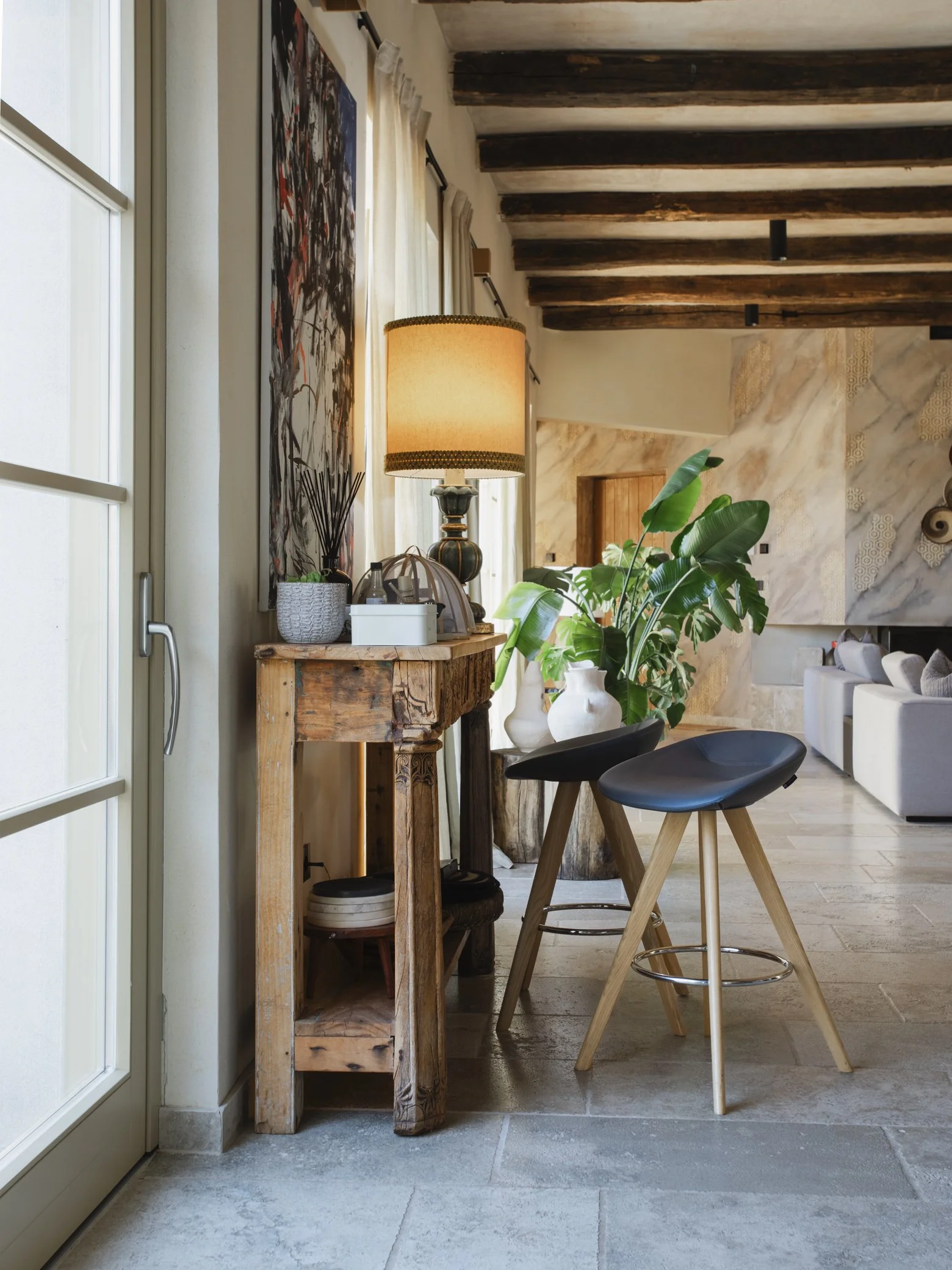 Cozy interior living space with a wooden console table next to a large indoor plant, creating a warm and inviting atmosphere.