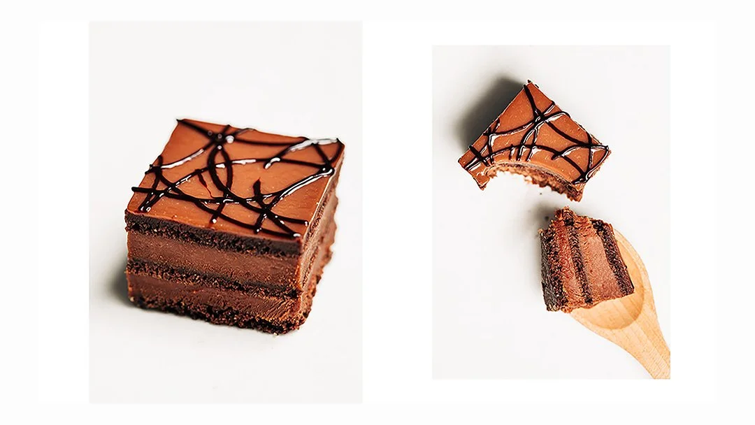 Chocolate layered cake with caramel frosting and chocolate drizzle on top, cut into pieces with one piece on a wooden spoon.