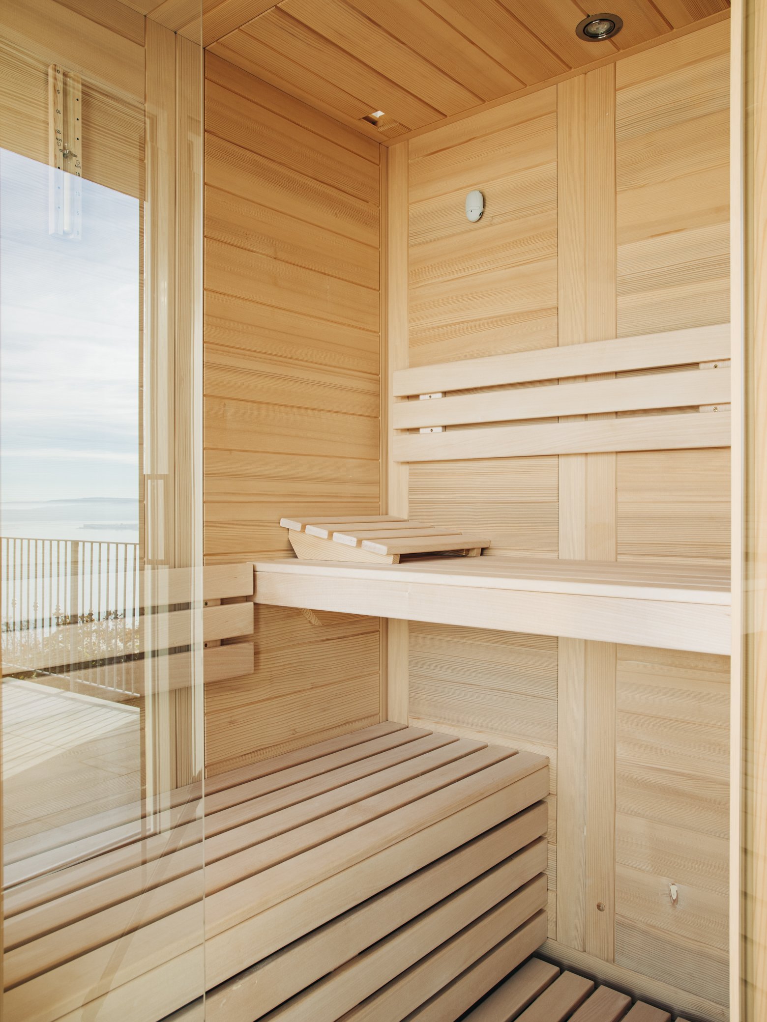 Interior of a wooden sauna with benches and a glass door.