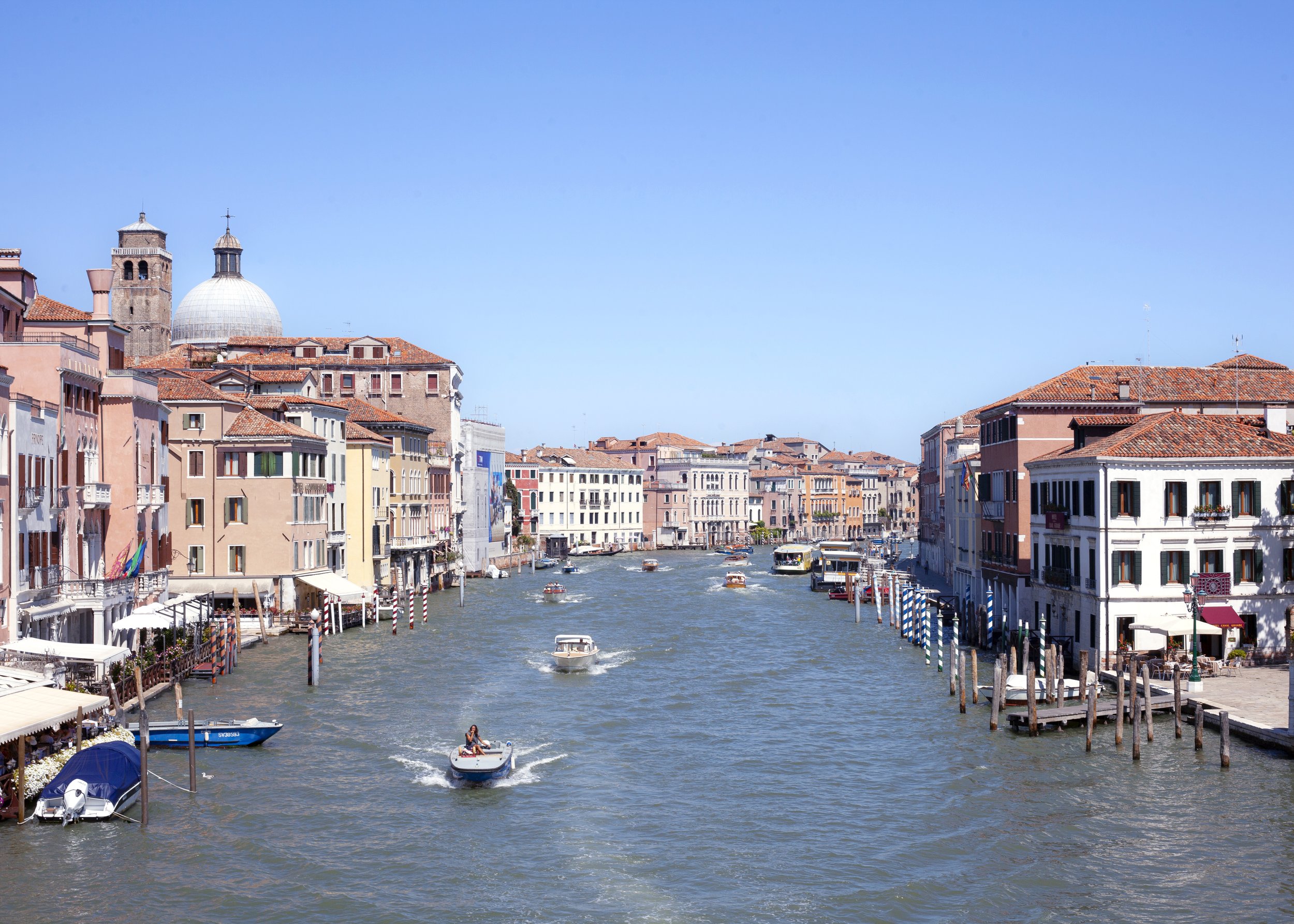 Canal in Venice with boats and colorful historic buildings on both sides, blue sky above.