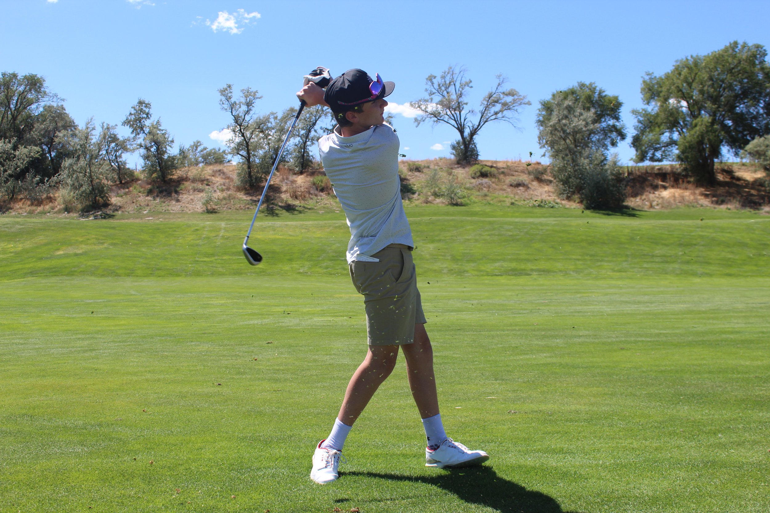 Male student watches a golf putt as it rolls across the green.