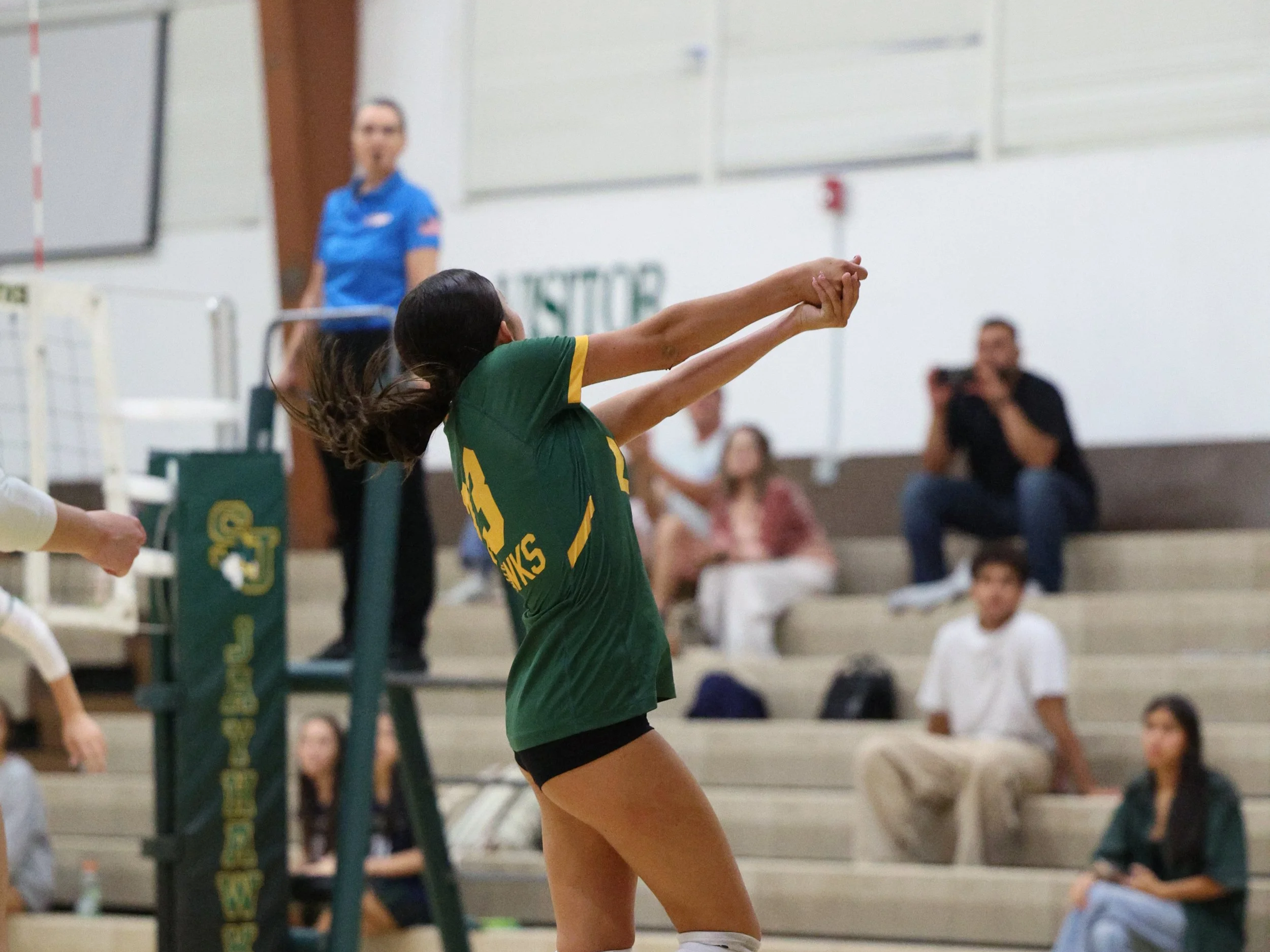 Female volleyball player serving the ball.